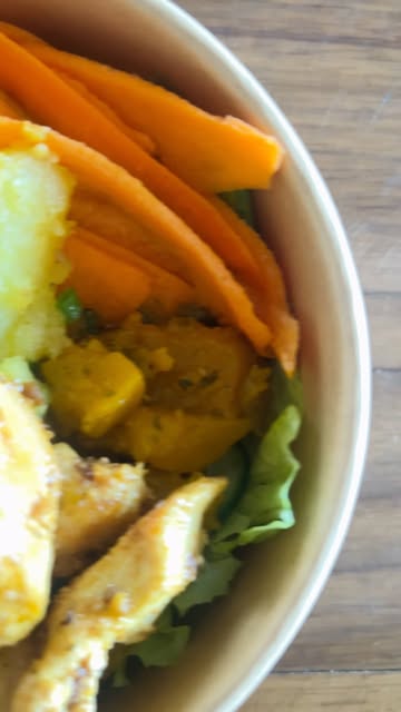 Detalhe de bowl com cenoura, abóbora, folhas e frango