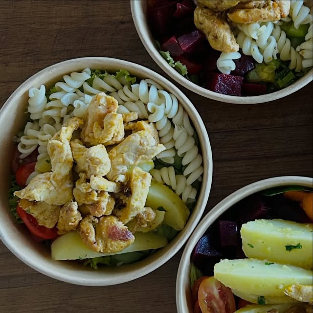 Três bowls lado a lado com fusilli, frango, tomate, beterraba e batata
